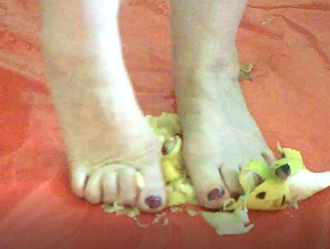 Herrin zerquetscht Banane mit nackten Füßen