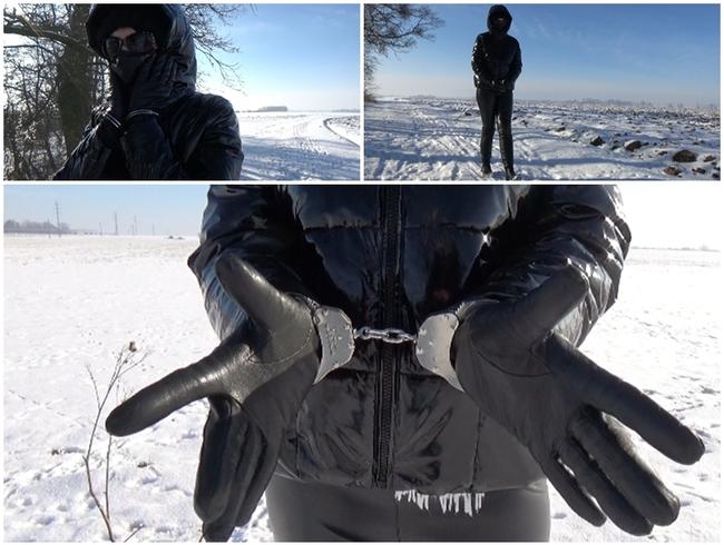 Winterspaziergang in einer PVC-Daunenjacke und Handschellen (Hände vorne)